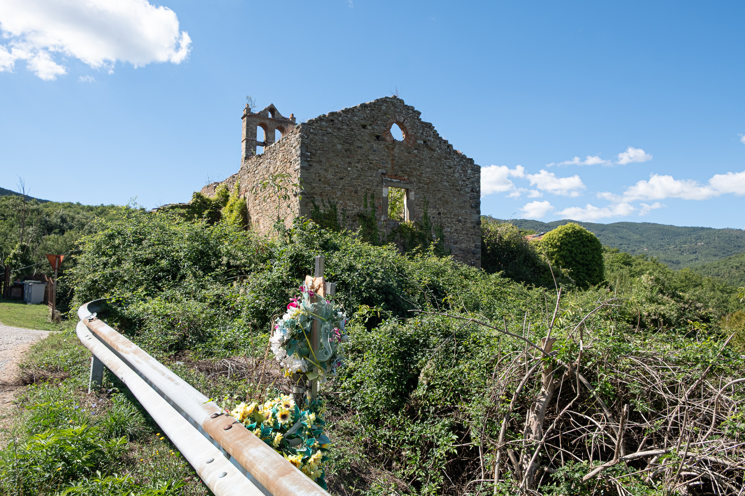 Kirchenruine am Straßenrand – davor ein Gedenkkreuz